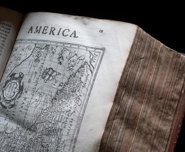 Detail of a printed book shows a full-page map and text at the of the page reading "America."